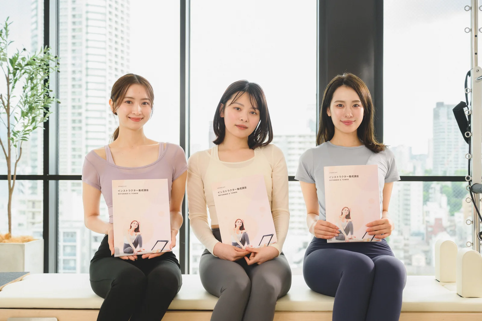 テキストを手に、スタジオのベンチに並んで座る3人のスタッフ