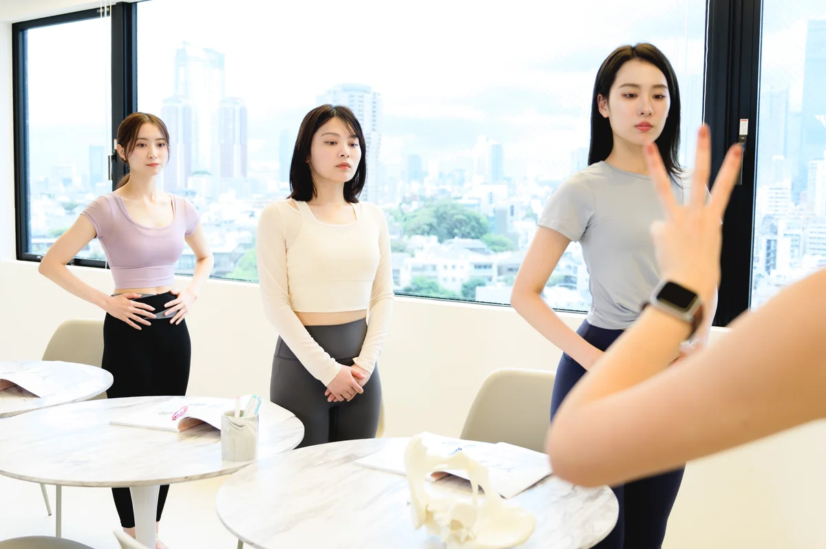 スタジオで、立った姿勢のワークを一緒に行う女性たち